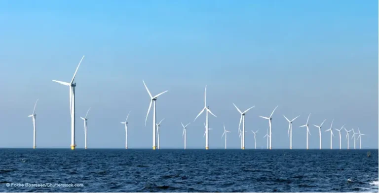 Many wind turbines in the ocean with blue sky and sea