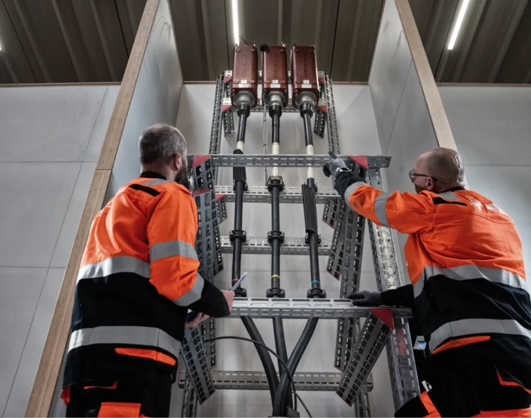 Man in orange safety gear pointing up at a termination