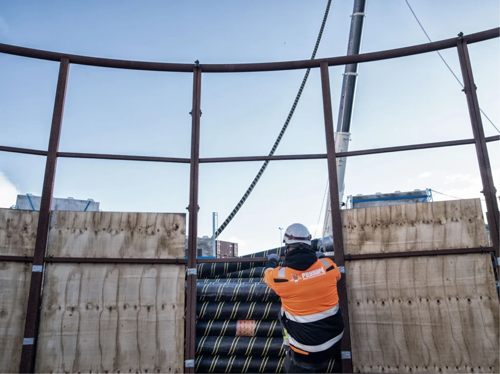 Man in safety clothing looking at clear sky and concrete wall